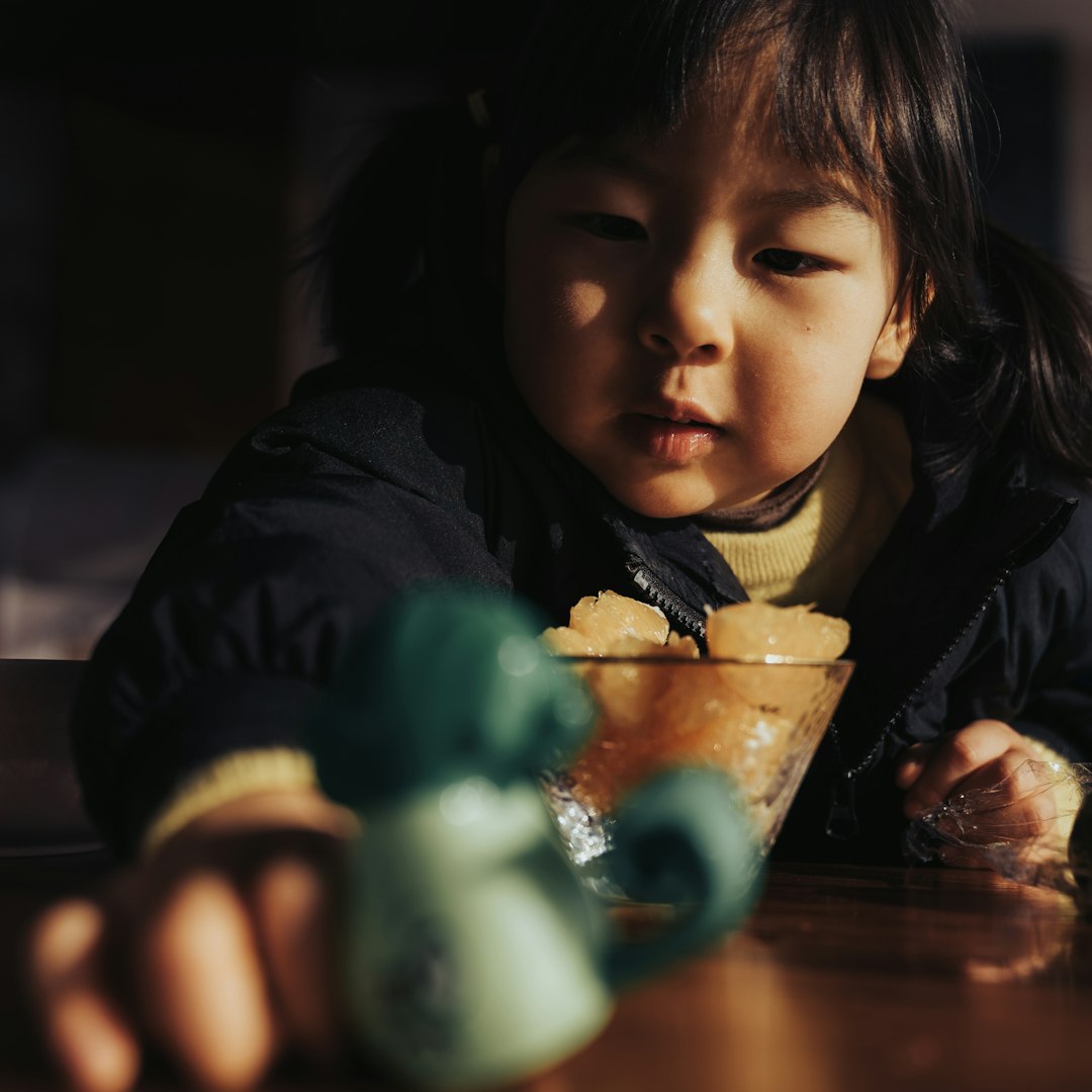 child in black jacket holding green plastic bottle
