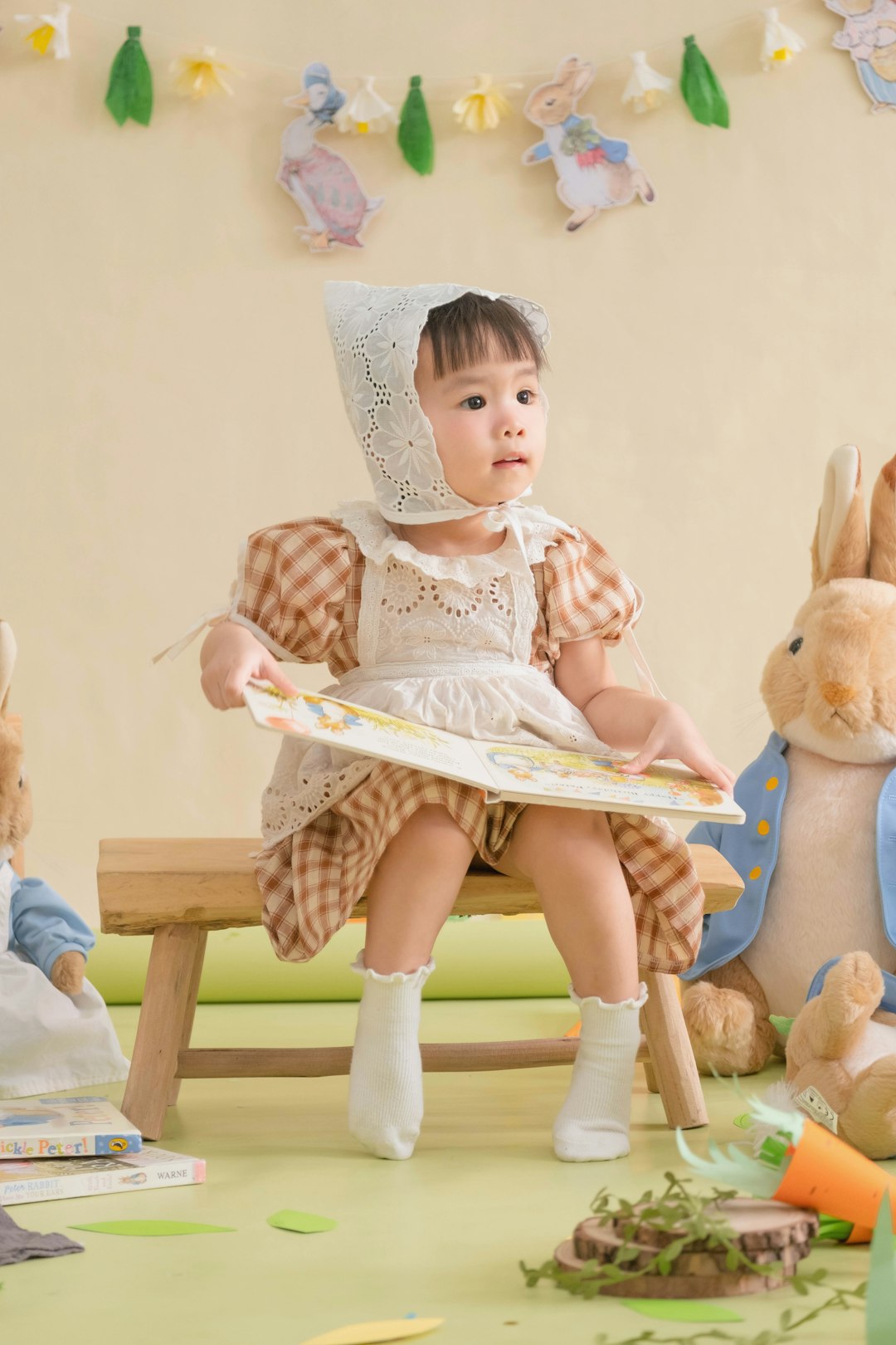 A little girl sitting on a bench next to stuffed animals